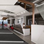 open office design with black flooring, white desks and wood feature beams. A women in a white shirt sits at one of the desks
