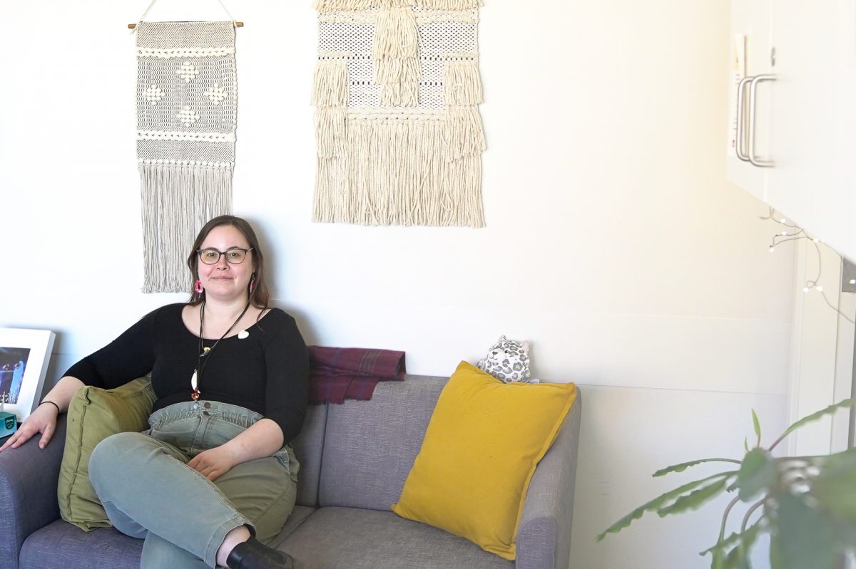 Sharlaine Glowatsky (she/they), the SVRC’s confidential intake & triage specialist on a couch in the Sexual Violence Resource Centre