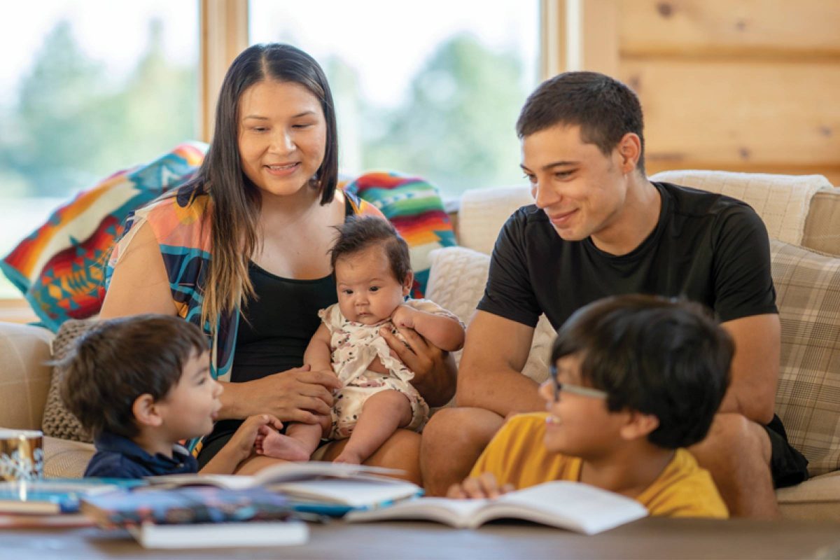A family sits together on a sofa.
