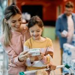 A mother and daughter look at a grocery label while shopping.