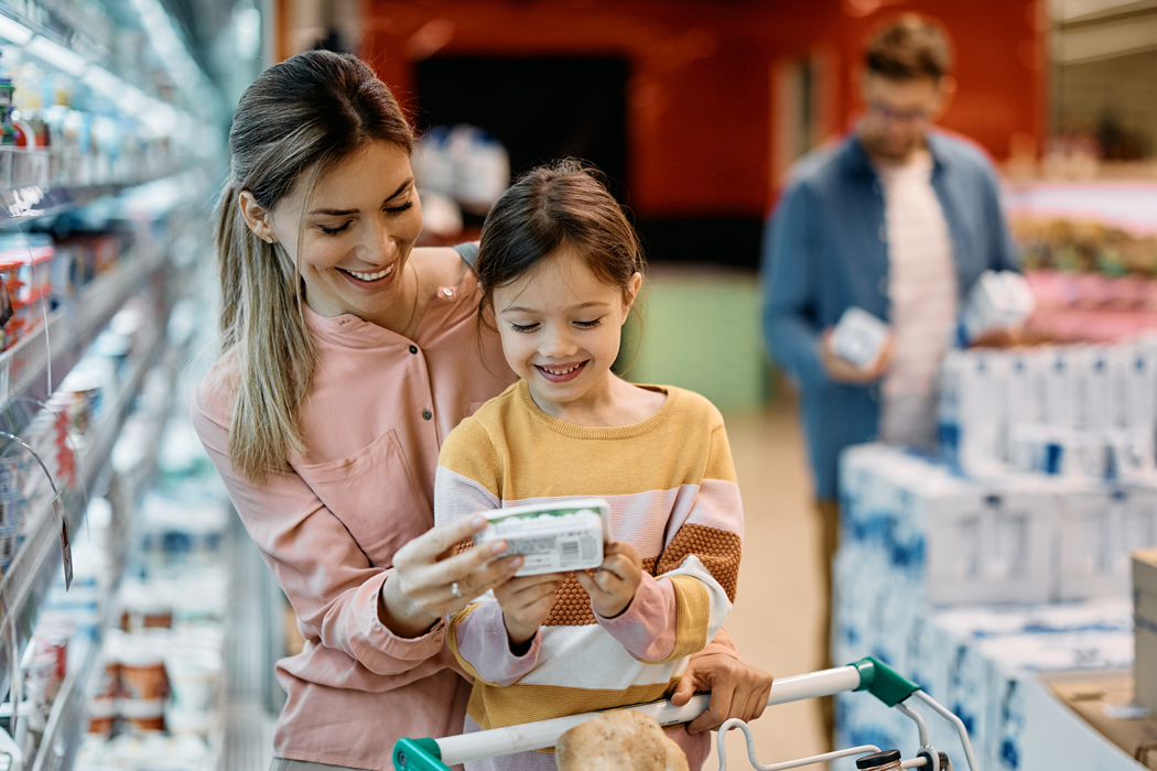 A mother and daughter look at a grocery label while shopping.