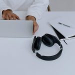 Close-up of computer, hands and headphones.