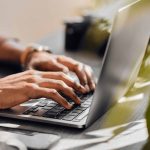 Hands typing at a desktop computer