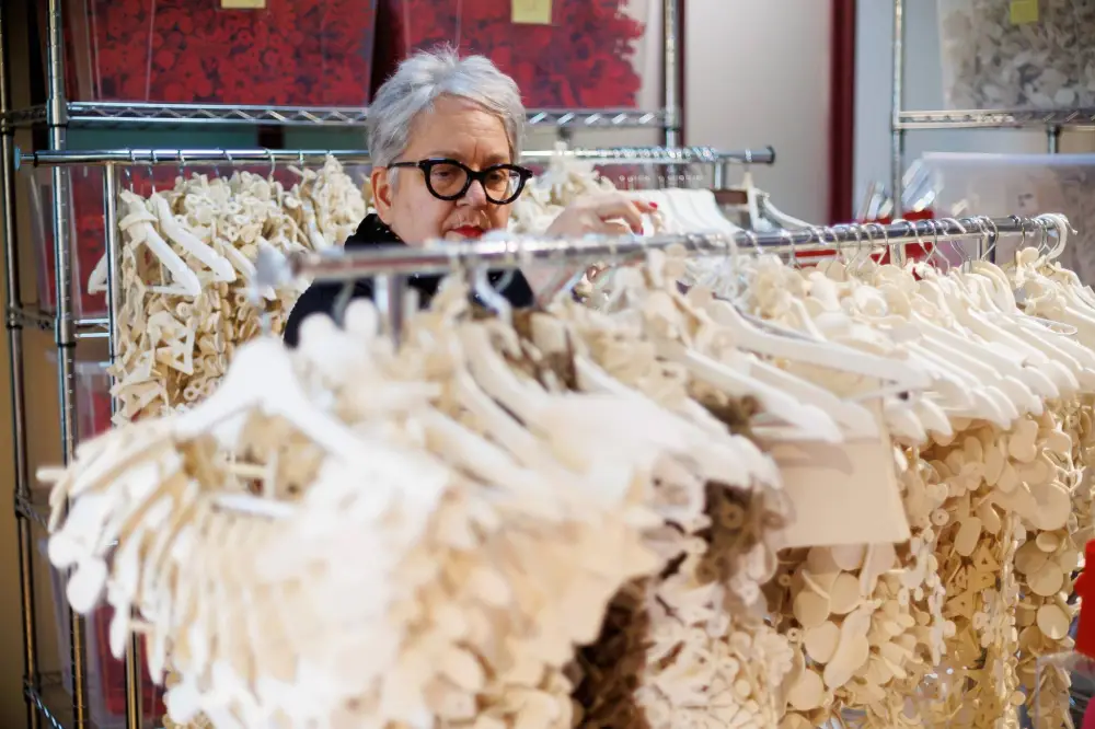 female with short grey hair overlooking a rack of unique shaped felt fabric jewlery