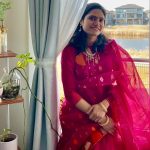 Woman in bright pink sari sitting on chair by the window