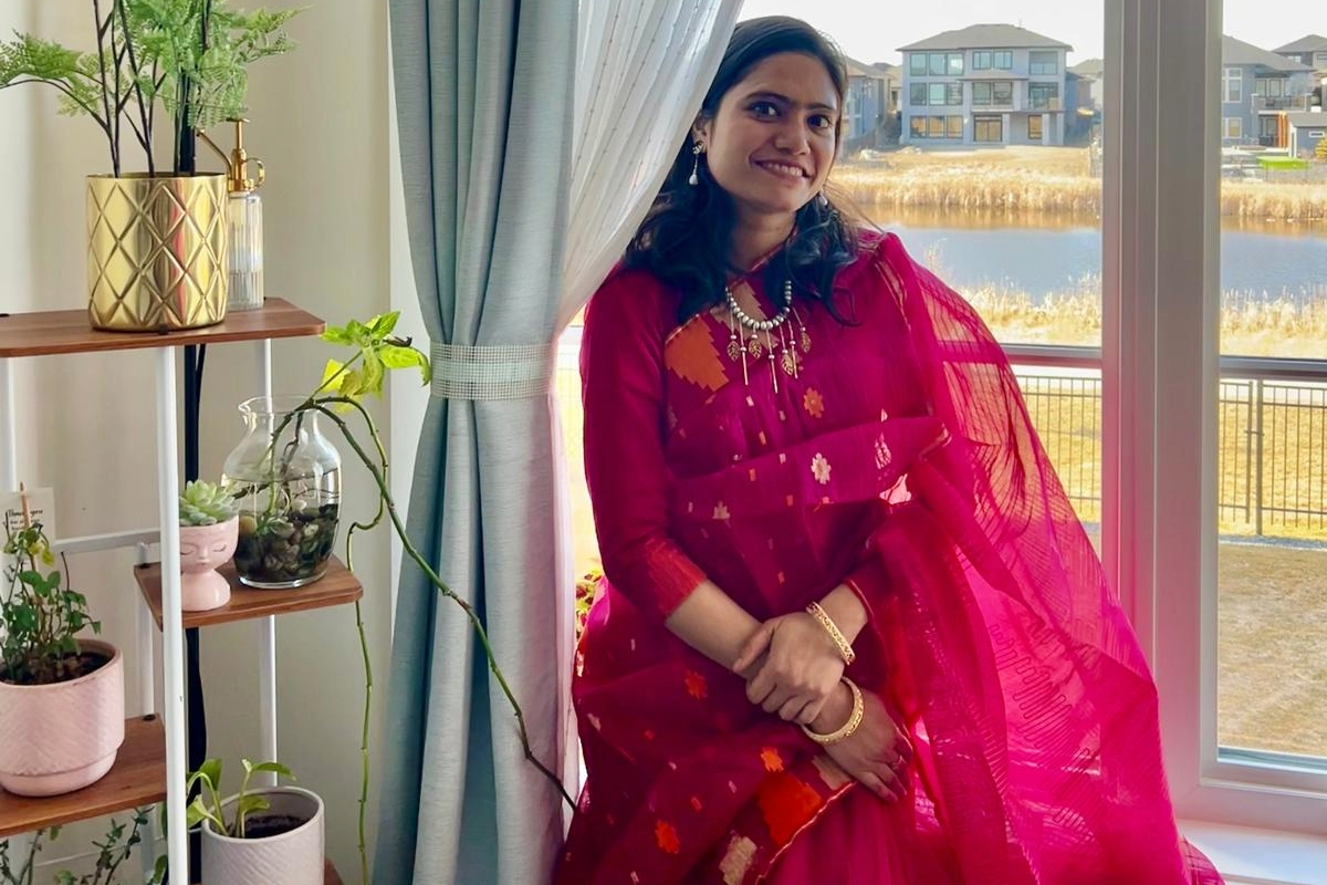 Woman in bright pink sari sitting on chair by the window