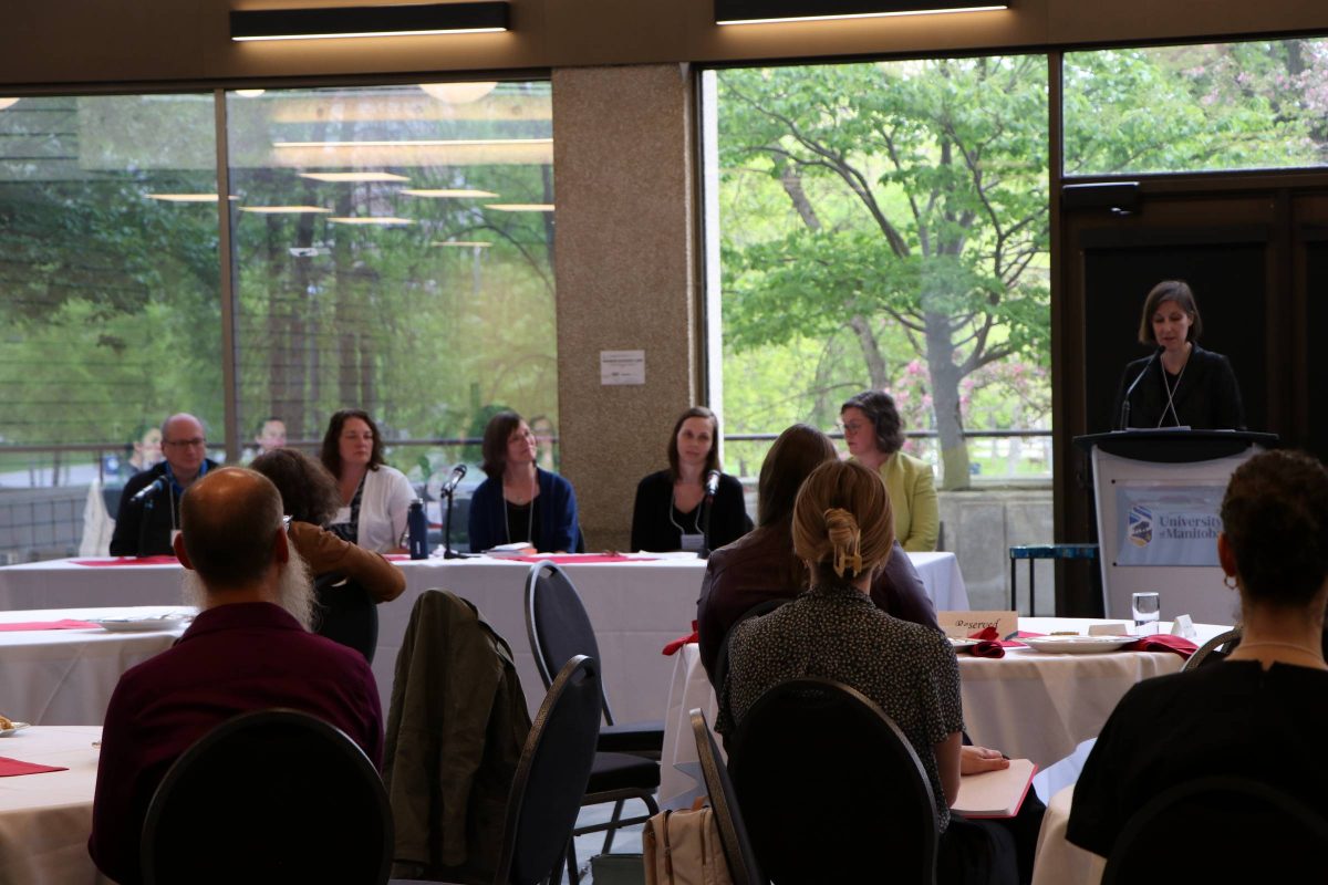 People at tables watching people at the front of the conference.
