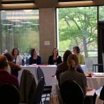 People at tables watching people at the front of the conference.