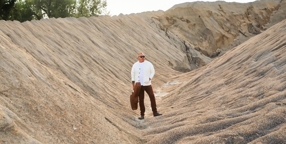 William Prince, holding a guitar case in his right hand.