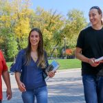 Two men and a woman walk across the UM campus.