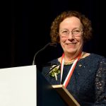 Estelle Simons smiling at a podium.