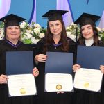 Laura Warkentin, Brooke-Lyn Wahoski and Emily Howarth wearing graduation caps and gowns, holding their degree parchments.