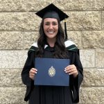 Photo of Juris Doctor Class of 2024 Valedictorian, Kali Faingold wearing a cap and gown and holding her degree in an official UM folder.