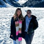 Two women in winter gear standing on a glacier smiling at the camera.
