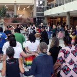 Dozens of people join hands and form circles around drummers in the middle.