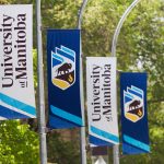 Four pole banners with the UM logo displayed.