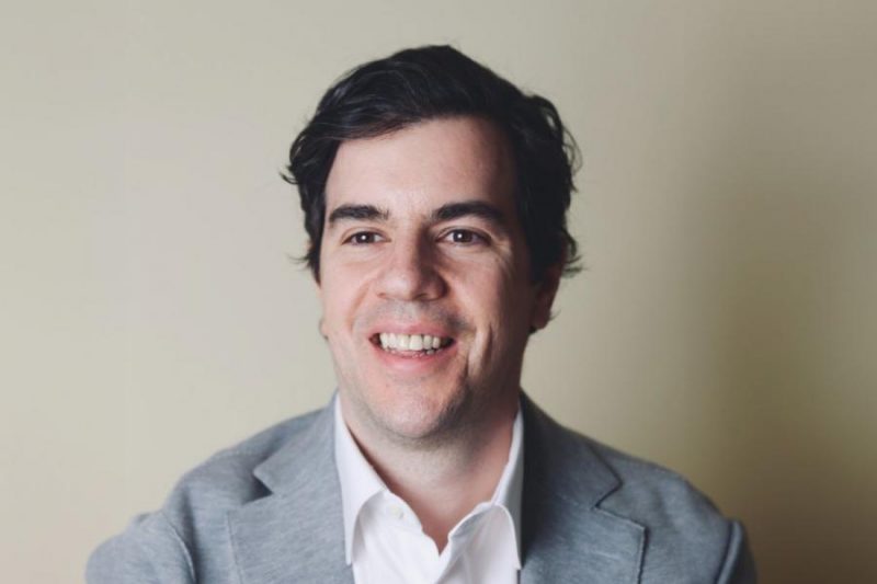 Headshot of new assistant professor Kenneth Grad wearing a white shirt and grey blazer smiling and looking left of camera.