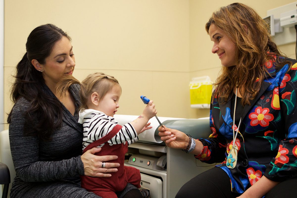 Physician checks out toddler being held by mom.