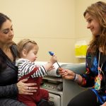 Physician checks out toddler being held by mom.