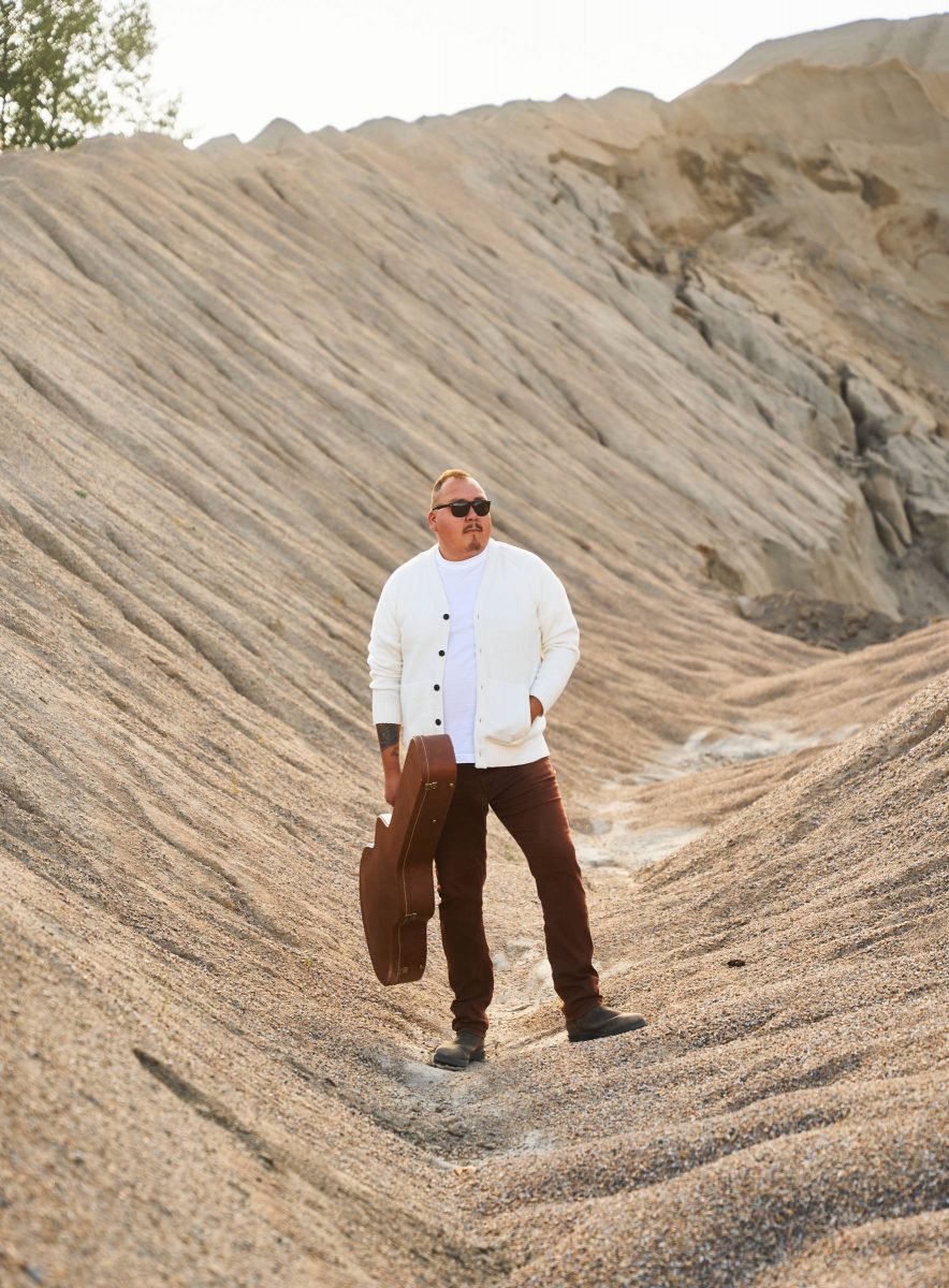 William Prince, holding a guitar case in his right hand.