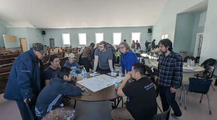 Students gathered around a table looking at building drawings