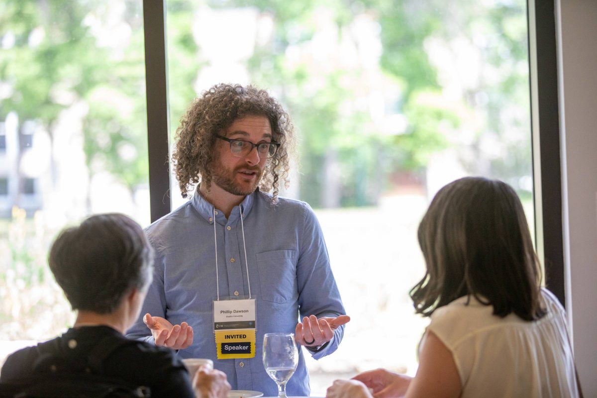 People talking around a table beside the window on a sunny day.