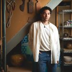 Joel Nichols stands in his basement art studio, surrounding by tools and ceramics