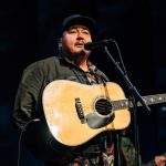 William Prince sings into a microphone from the stage