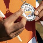 A participant holding a medal and a feather