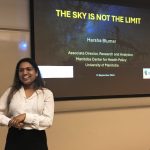 Dr. Harsha Blumer, giving a presentation with a screen behind her