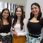 Three female Indigenous students in the lobby of the pinning ceremony. The student in the middle holds her UM nursing pin.