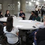 A group of students around a tablein a discussion.