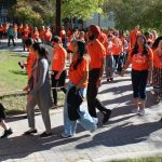 Dozens of people wearing orange shirts walk at the Fort Garry campus.