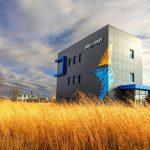 The Idea Start logo features a gold and blue lightening bolt representing the spark of innovation, which now decorates the exterior walls of the Smartpark Event Centre with a field of yellow grass in the foreground.