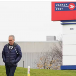man and woman walking in front of Canada Post sign