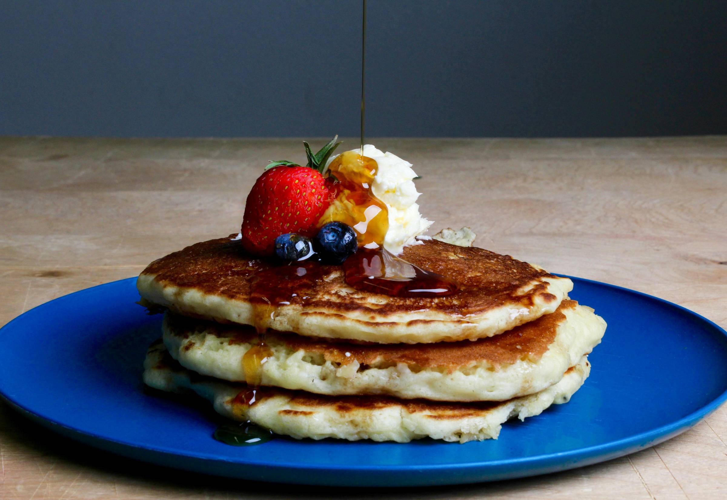 Maple syrup being poured on a stack of pancakes (photo by Sydney Troxell)