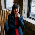 Photo of Elise Epp a smiling woman with long dark hair wearing a blue and red knit dress.