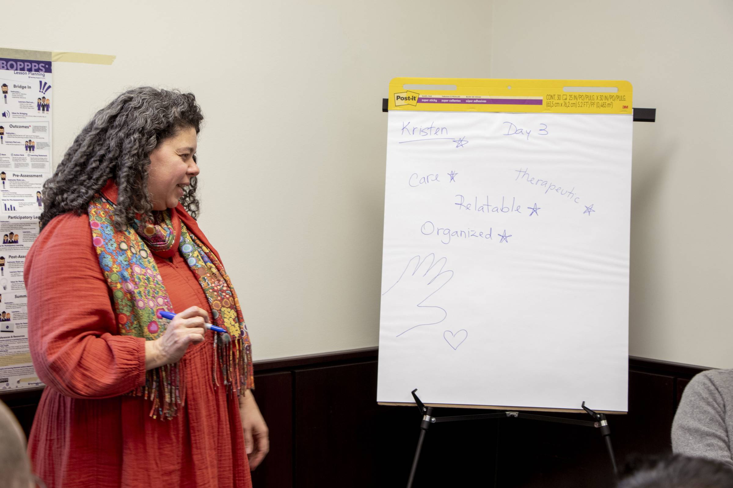 Brazillian woman with Black and grey curly hair (Cintia Costa) facilitating as session.