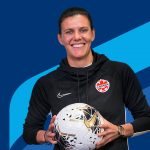 Christine Sinclair holding a soccer ball in front of University of Manitoba branding colours