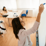 Instructor in classroom writing on a whiteboard