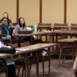 A presenter stands at the front of a seated audience during a 3MT Challenge Heat.