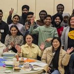 a large group of people gathered around a table at the UM 2024 Better Together event.