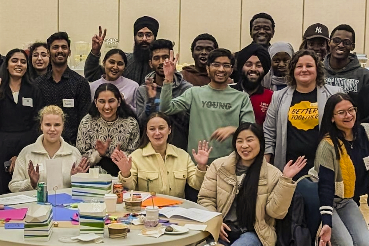 a large group of people gathered around a table at the UM 2024 Better Together event.