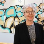 Kellie Thiessen stands in front of a mural at the College of Nursing.