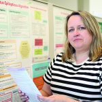 Lisa Knisley stands by a research poster.