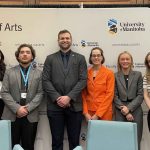Group of six people standing in front of a banner, all with their hands crossed in front of their bodies.