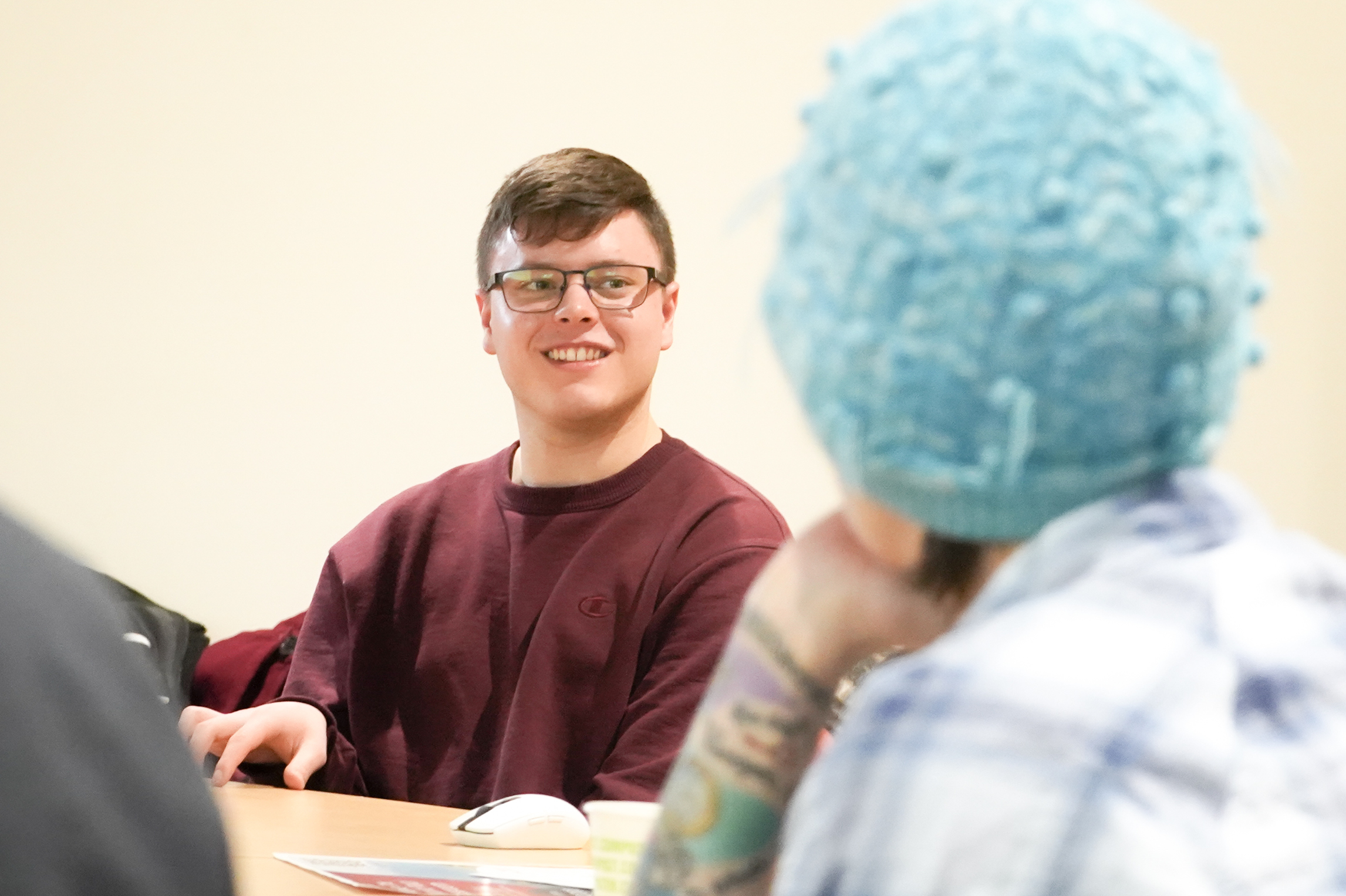 Student talking with another student on a rounded table while smiling.