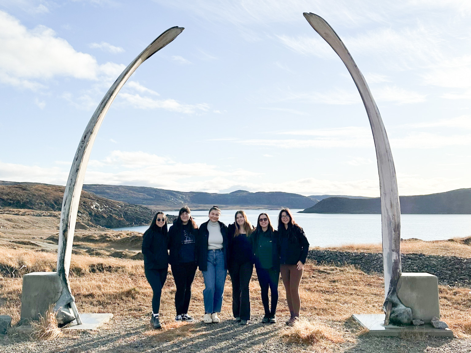 ICE alumni stand beneath the whale bone arch in Niaqunngut (Apex), a scenic area of Iqaluit.