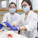 Two dental students working on a mold of a mouth.