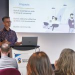 Man presenting to a classroom full of adults, using a PowerPoint presentation.